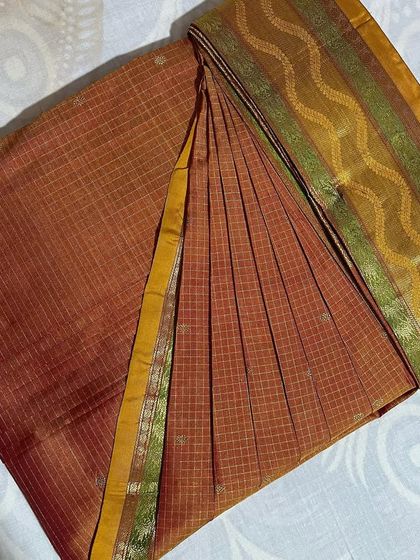 This earthy-toned checked saree is ready to be draped. I ensure the lines of the pattern align for a neat, professional look.