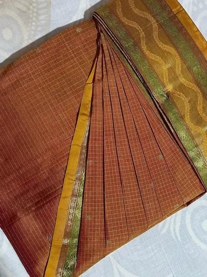 A checked brown saree with a multi-colored border, neatly folded.