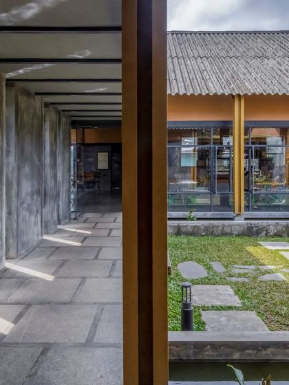 Looking from a covered corridor into the open-to-sky courtyard. This view shows how we use layers of built and unbuilt spaces to create a dynamic experience, drawing the eye towards the green landscape.
