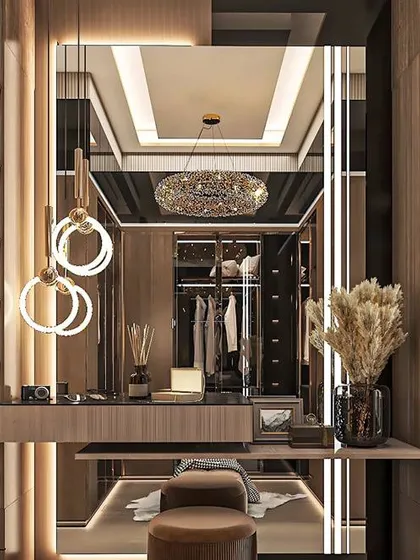 This is a walk-in wardrobe we designed for a client, featuring a dedicated vanity table with a large mirror and custom lighting. The glass-fronted cabinets with internal lighting make it easy to see and organize clothes and accessories.