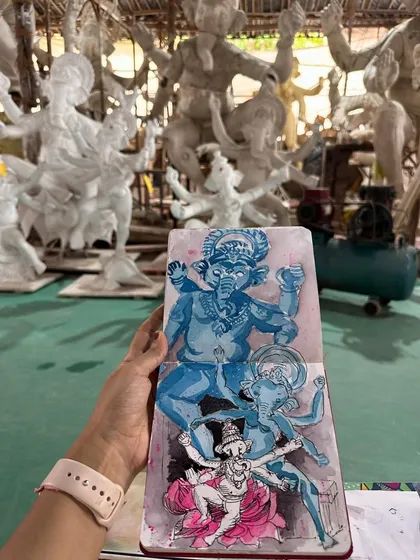 My blue-toned Ganpati sketch held up in the workshop, surrounded by the white clay idols that served as my inspiration. It shows the contrast between the raw material and the artistic interpretation.