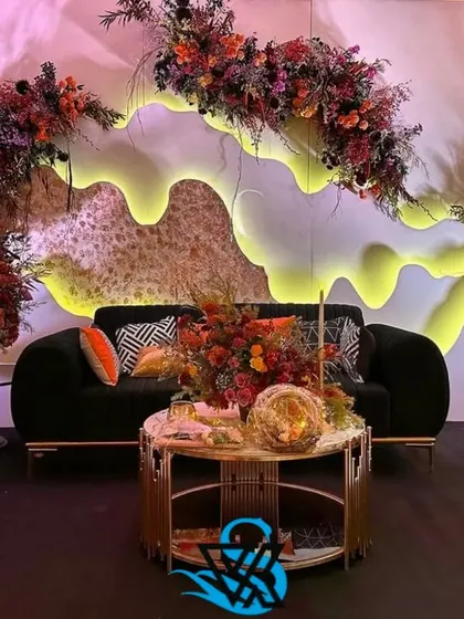 A closer view of the modern lounge setup, showing the texture on the backdrop and the mix of patterned cushions that add visual interest to the black sofas.