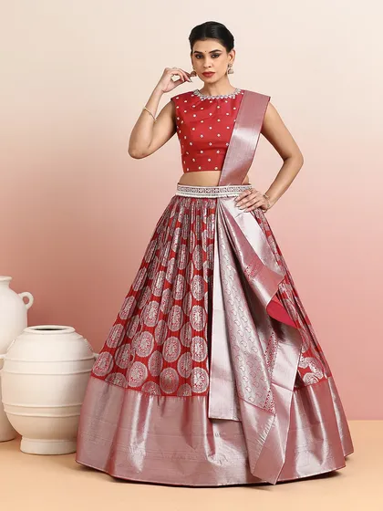 A stunning red and silver Banarasi lehenga, styled as a half-saree. The intricate weave and bold color make it a perfect choice for a bride or wedding guest.