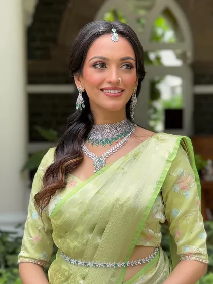 A close-up on the face, showing the perfect harmony between the makeup, the diamond maang tikka, and the layered necklaces. The skin looks luminous and healthy.