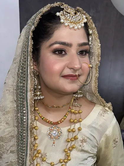 A detailed close-up of our elegant bridal makeup. This look features soft, blended eyeshadow, precise eyeliner, and a natural blush, all designed to enhance her features while complementing the intricate gold jewelry and attire.
