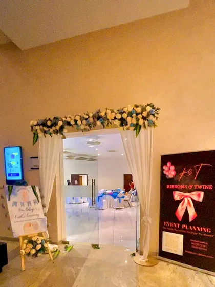 A clear view of the entrance decor, including the personalized easel stand welcoming guests to the baby's cradle ceremony.