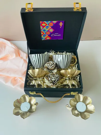 Another angle of the premium ceramic cup and golden elephant T-light holder set. The combination of black, white, and gold in this suitcase hamper is timeless and elegant.