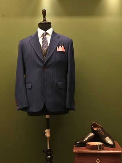 This is the same timeless navy pinstripe suit, presented here as a still image. It allows for a longer look at the harmony between the suit, the vest, the striped tie, and the contrasting pocket square, a complete sartorial statement.