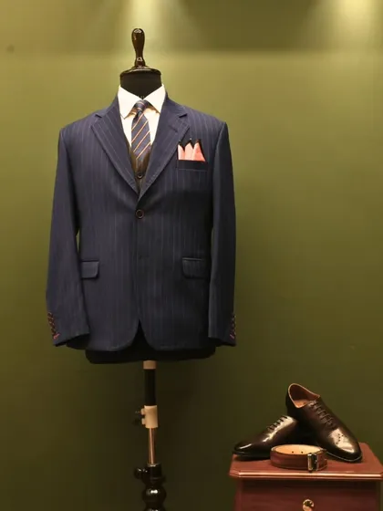 This fully styled navy pinstripe suit on a mannequin, paired with leather shoes, shows a complete look. It exemplifies how we approach outfitting for a powerful and cohesive presence.
