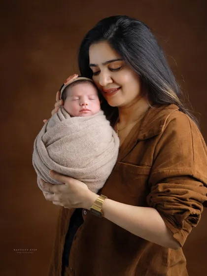 A mother's gentle embrace. This portrait focuses on the tender bond between a mother and her newborn, set against a classic, warm brown backdrop for a timeless feel.