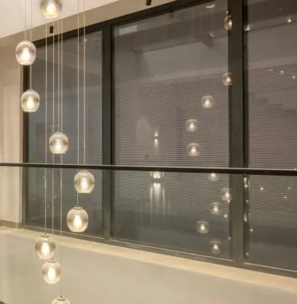 The cascading glass orb chandelier is reflected in the large windows, creating a beautiful play of light and reflection in this multi-level space.