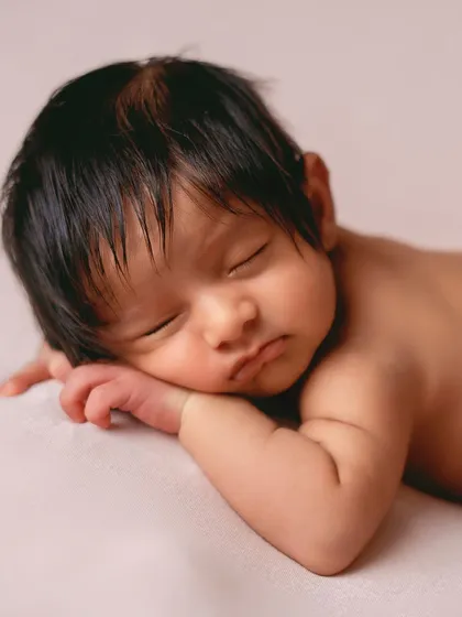 The "tushy up" pose is a newborn photography classic. It shows off their sweet little back rolls and peaceful sleeping face on a simple, clean background.
