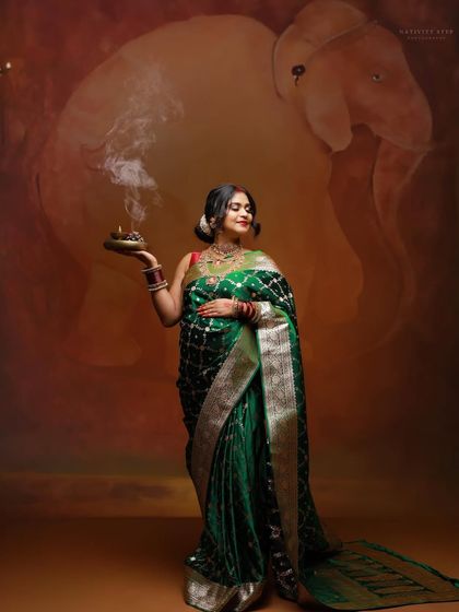 This portrait showcases the mother-to-be holding a traditional diya, symbolizing light and life. The artistic backdrop with the elephant motif adds a layer of cultural significance.