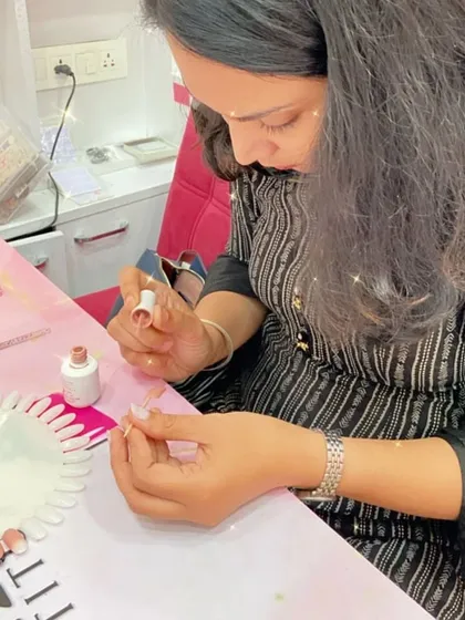 A student practices applying a base color, the first step in creating a beautiful nail art design.
