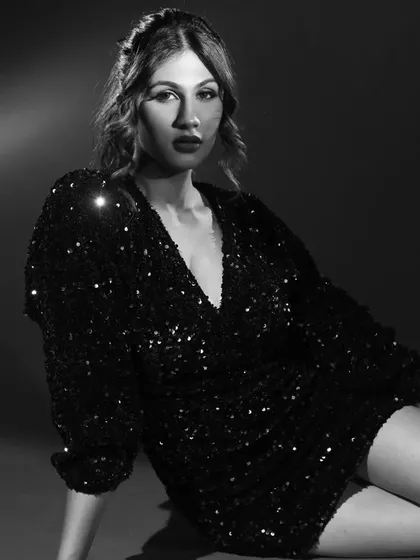 The shimmering ensemble and dramatic makeup create a captivating image in black and white.