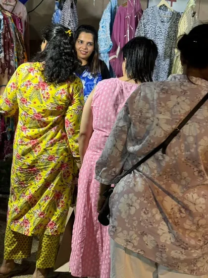Shoppers browsing through colourful printed kurtas at an outdoor stall, enjoying the festive market atmosphere.