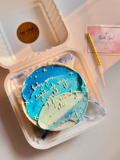 A romantic message on a dreamy, sky-blue ombre cake. The text "baby you light up my world" is complemented by tiny, hand-piped stars.