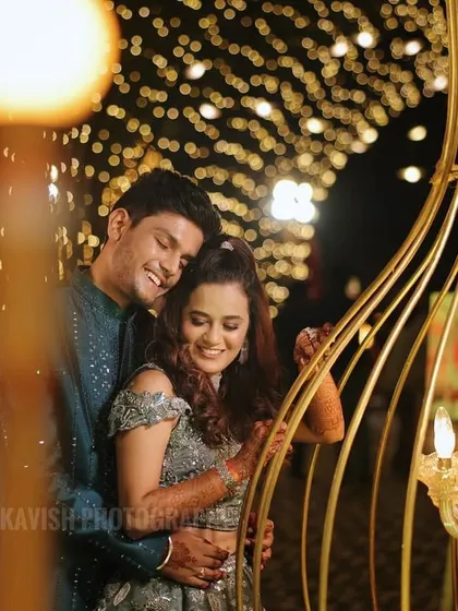 A tender embrace under an arch of golden lights, capturing the romance of the sangeet night.