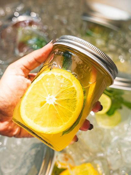 A hand holding our orange and mint soda, showcasing the fresh fruit inside.