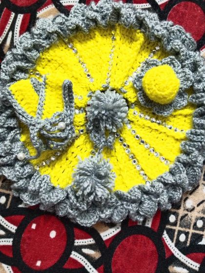 A cheerful yellow and grey winter set. This woolen dress is decorated with grey pom-poms and comes with a matching crochet bag for Kanha Ji's essentials.