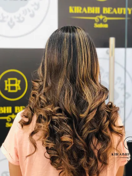 The "after" of the previous image. We added beautiful balayage highlights and styled the hair in bouncy curls to create a stunning, dimensional look.
