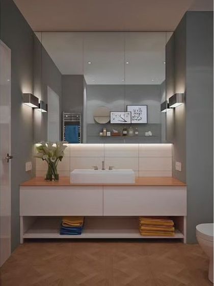 A clean and simple bathroom with a wide vanity and open lower shelf for towel storage. The large mirror and dual wall sconces make the space feel bright and spacious.