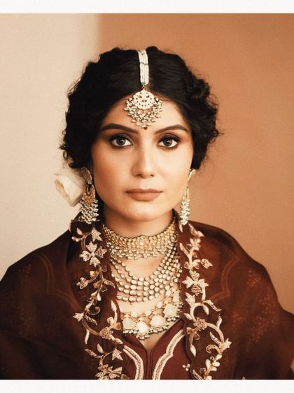 A classic portrait of our bride. Her look features heavily layered necklaces and a statement maang tikka, perfectly embodying a regal and timeless aesthetic.