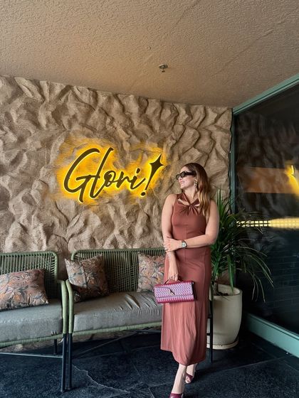 The same brown dress, but this time styled with a contrasting magenta clutch. This shows how a simple pop of color can transform a monochromatic outfit and add a playful element.