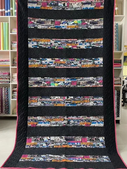 A "Graffiti" quilt with strips of chaotic, colorful fabric separated by solid black.