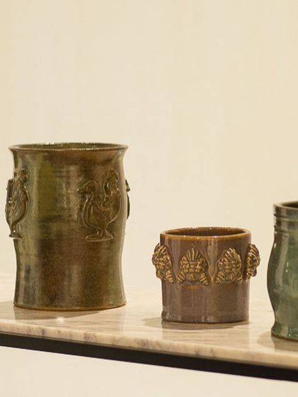 A collection of rustic planters featuring detailed sprig work. The rooster and leaf motifs are pressed from molds and applied by hand, giving these pots a classic, handcrafted feel.