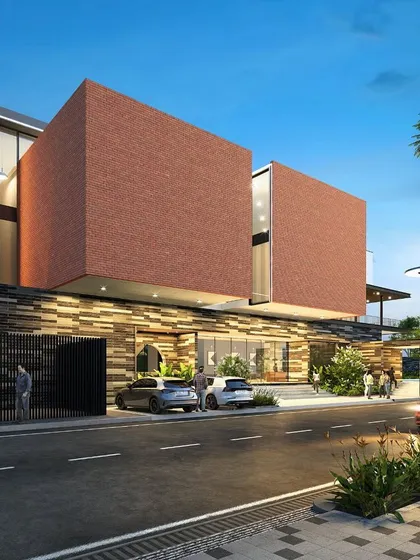 A night-time rendering of a luxury clubhouse for a 7.1-acre residential community in Bengaluru. The design uses a powerful combination of brick cladding, textured stone, and warm ambient lighting to create a grand and welcoming entrance.