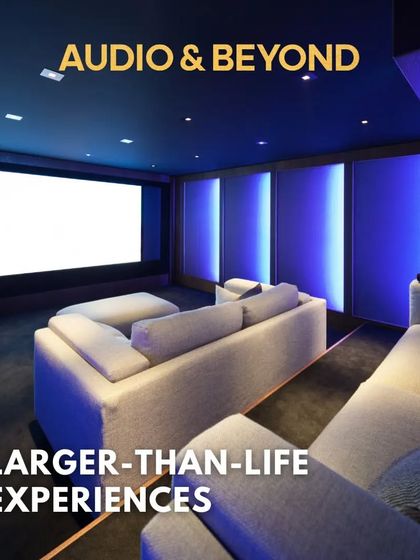 This is what a larger-than-life experience looks like. A custom-designed home cinema with multi-level sofa seating, ambient blue wall lighting, and a massive screen ready to transport you into the movie.