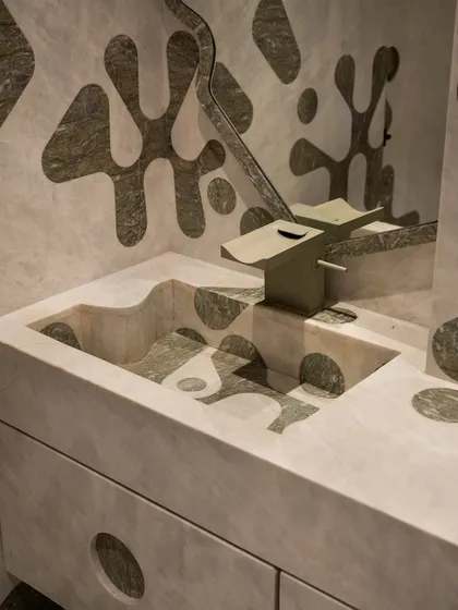 We pushed the boundaries of material and geometry in this powder bathroom. The walls, integrated vanity, and even the sculptural sink basin feature a bold, amoeba-like pattern inlaid in contrasting marble. This required immense precision from our artisans to carry the inlay seamlessly from horizontal to vertical surfaces.