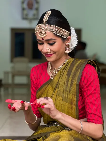 The application of Altha is a ritual in itself. This bright red dye on the hands and feet is a crucial part of the Bharatanatyam aesthetic. My process is meticulous, ensuring clean lines and a vibrant color that highlights the intricate mudras and footwork of the dancer.