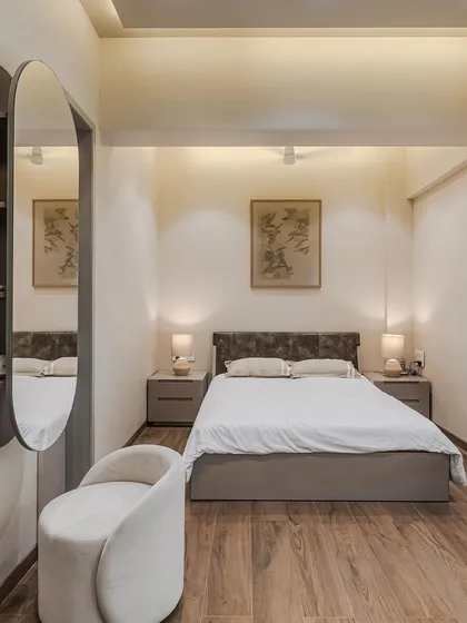 A full view of a bedroom designed for simplicity and style. Our modular bed features a sleek leather back and ample under-bed storage, paired with matching side tables. The warm wood flooring and soft lighting create a tranquil and inviting environment.