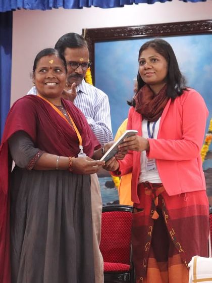 Dr. Sushama Maurya presenting an award to a participant at the conference, recognizing contributions to the field of yoga.