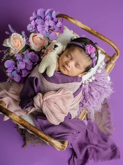 A floral haven for the tiniest treasure. This dreamy setup uses shades of lavender and pink, with a miniature bed and soft wraps to create a magical, fairytale-like portrait.