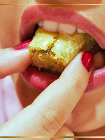 That first bite feeling. A close-up capturing the indulgent and satisfying experience of eating a piece of our authentic, crispy baklava.