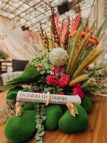 A centerpiece with a 'Behind the Bump' fun facts scroll, adding a personalized and interactive element for guests.