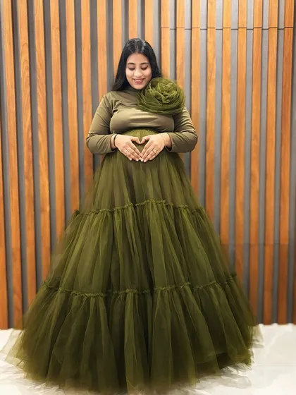 Our olive green tiered gown is a unique and stylish choice. It features a comfortable full-sleeve top with a statement flower and a full, flowing tulle skirt that photographs beautifully.