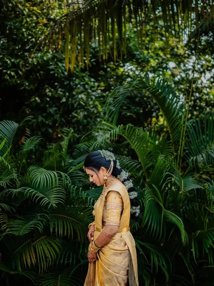 A side profile showing her traditional hairstyle, a neat bun adorned with a string of jasmine flowers.