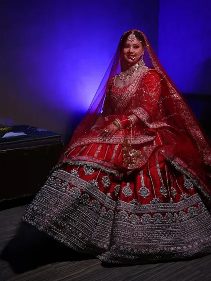 A full view of the bride in her stunning red lehenga. The makeup enhances her features without overpowering her natural beauty.