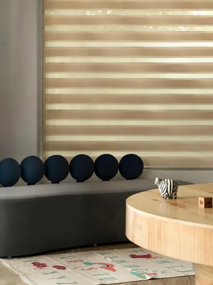 A serene waiting area with a curved grey bench and spherical cushions. The space is designed to be calming for parents, with soft, ambient light filtering through the blinds and a minimalist aesthetic.