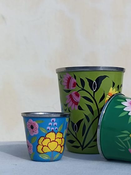 A set of colourful, hand-painted steel tumblers, each with a unique floral design.