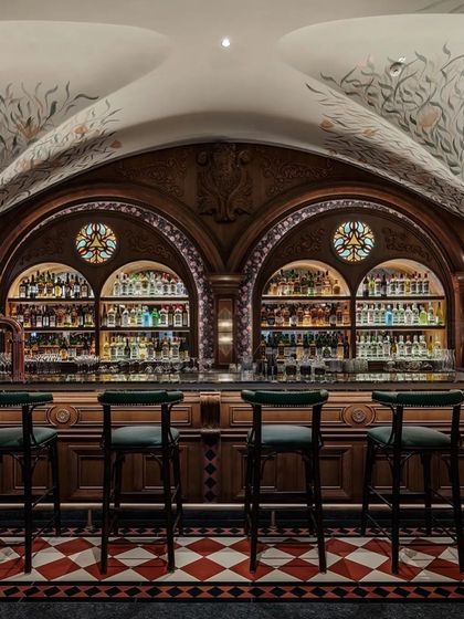 The main bar is a masterpiece of craftsmanship, with carved wooden arches, stained glass details, and a beautifully organized back bar.