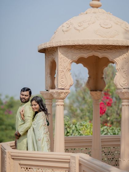 A quiet, affectionate moment captured on a palace balcony. The soft natural light and elegant setting create a timeless and romantic image.