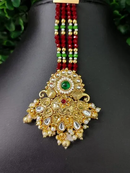 A unique maang tikka with a beaded strand, featuring a traditional pendant with kundan work.
