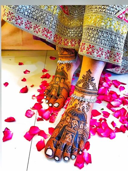 A stunning shot of a bride's feet adorned with intricate doli (palanquin) mehandi, set against a bed of rose petals.