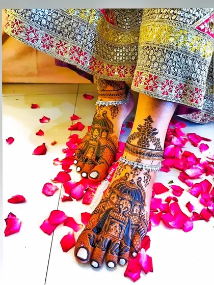A stunning shot of a bride's feet adorned with intricate doli (palanquin) mehandi, set against a bed of rose petals.