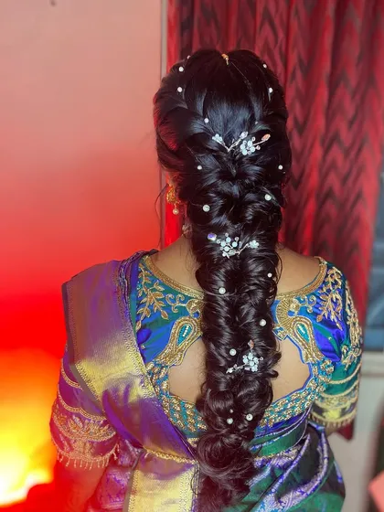 A modern twist on a traditional braid. This messy fishtail braid, decorated with delicate pearl and crystal accessories, is a popular choice for receptions and sangeeths.
